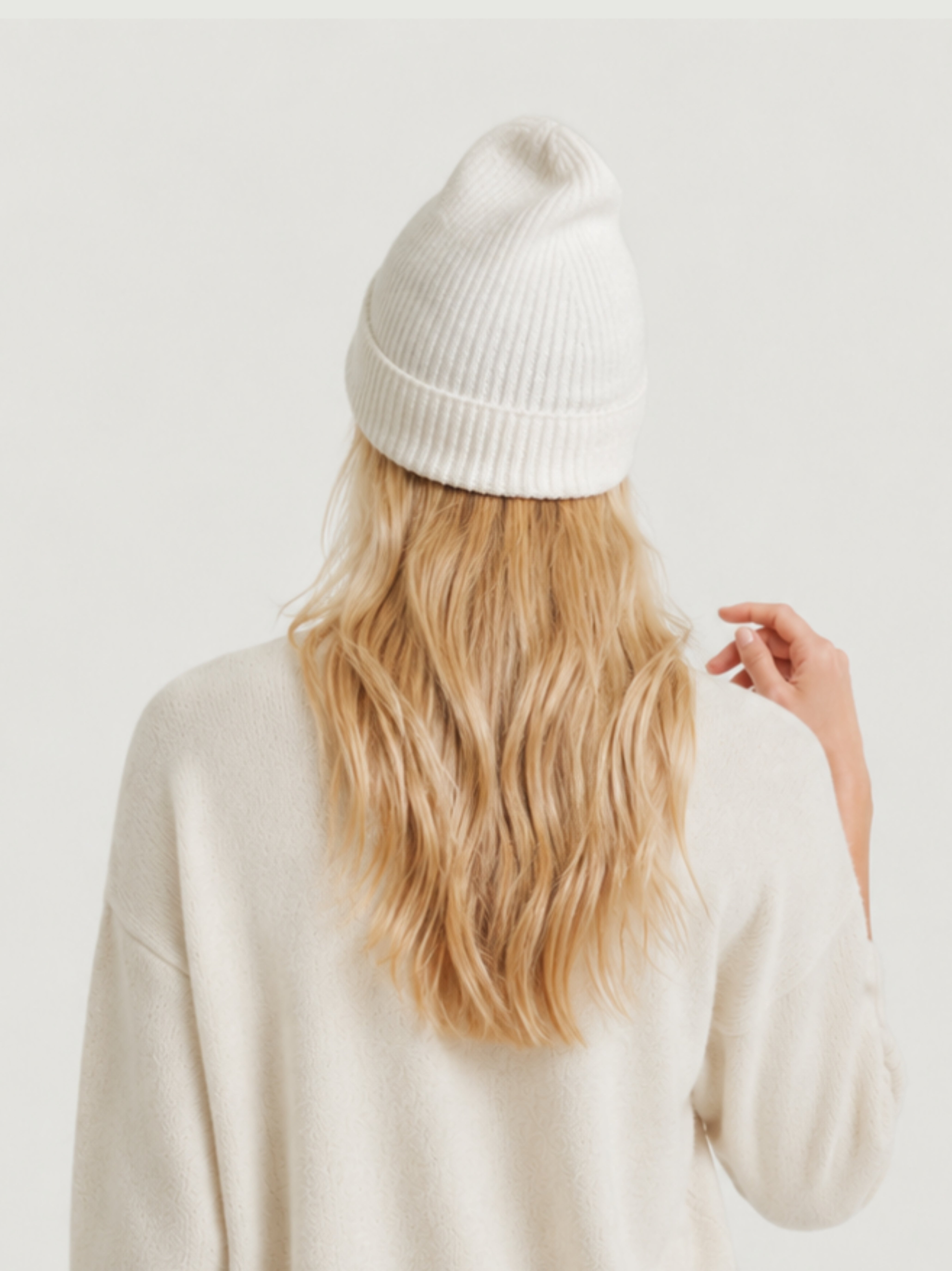 Vista posteriore modella indossa berretto beanie bianco a coste verticali, risvolto alto e calotta arrotondata