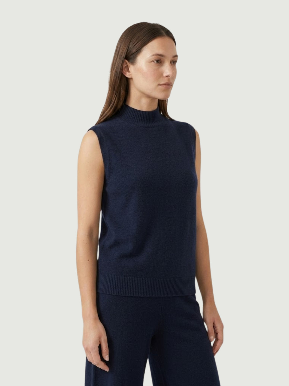 Vista laterale modella indossa gilet smanicato con collo a lupetto blu scuro