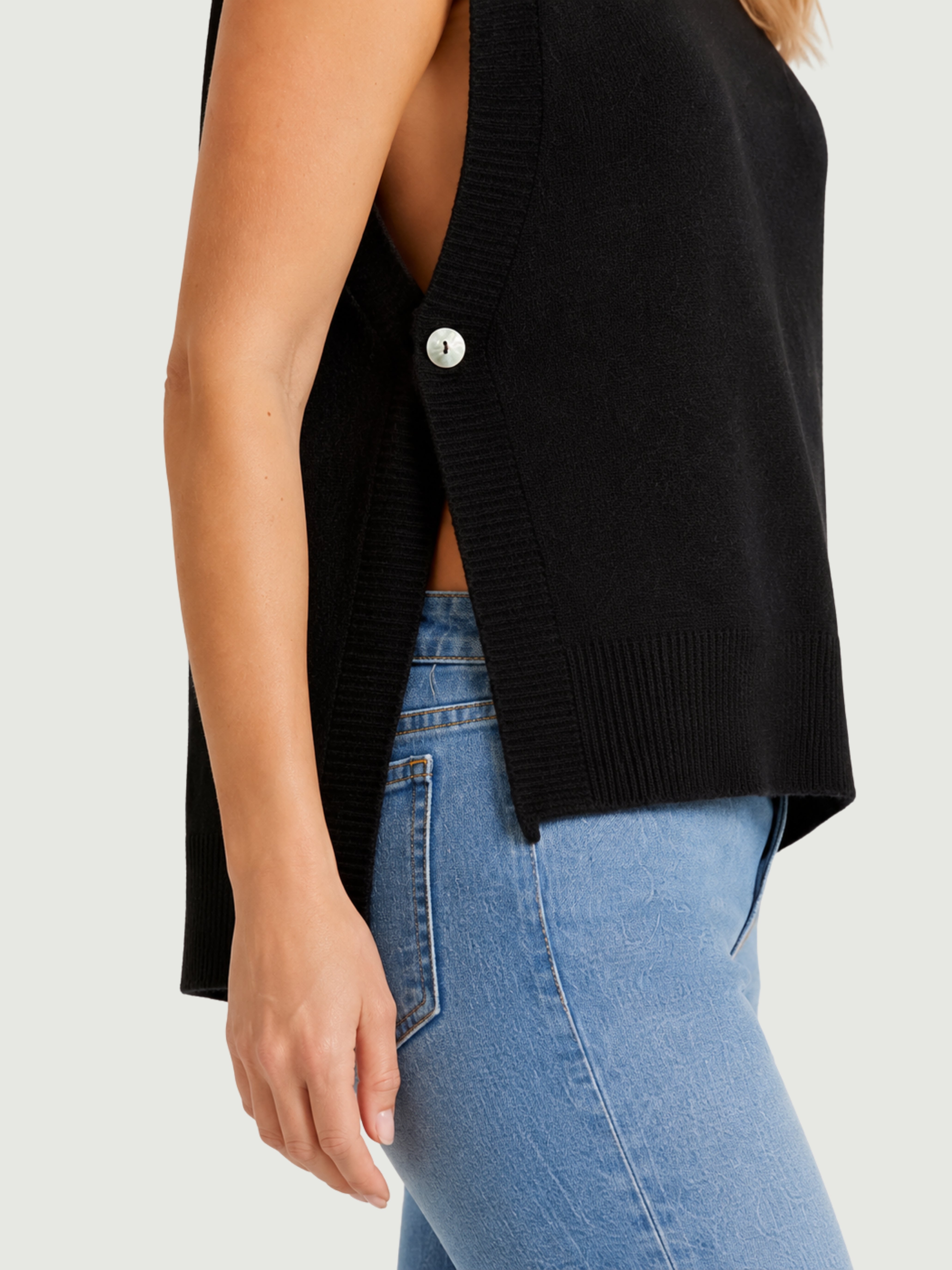 Dettaglio gilet smanicato nero con aperture laterali chiuse da bottoni in madreperla