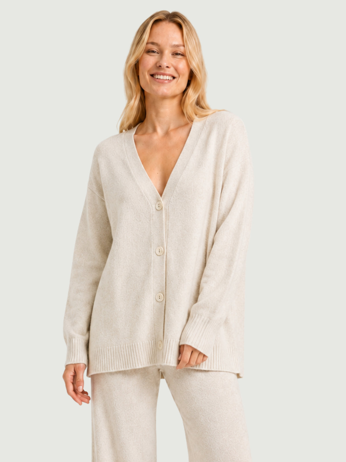 Modella indossa cardigan over bianco panna, scollo a V, manica lunga con polsino a costine, chiusura con bottoni effetto madreperla SARA - BiMOR