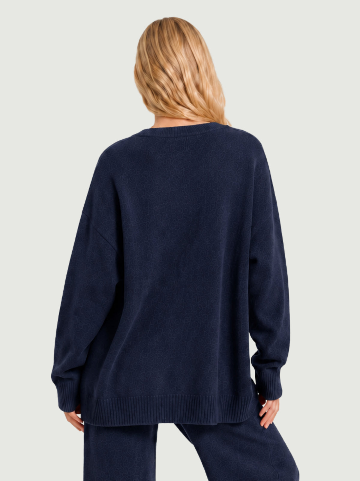 Vista posteriore modella indossa cardigan over blu scuro, scollo a V, manica lunga con polsino a costine, chiusura con bottoni effetto madreperla