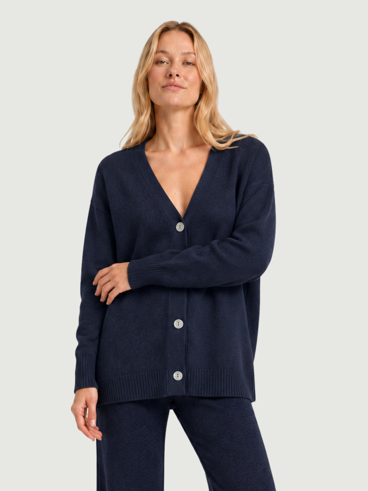 Modella indossa cardigan over blu scuro, scollo a V, manica lunga con polsino a costine, chiusura con bottoni effetto madreperla SARA - BiMOR