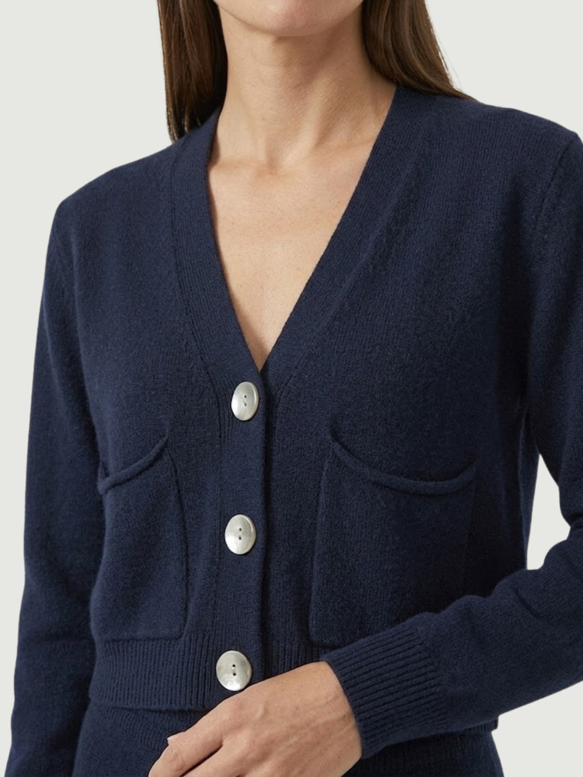 Dettaglio cardigan cropped blu scuro con scollo a V, chiusura frontale con bottoni effetto madreperla, taschini applicati