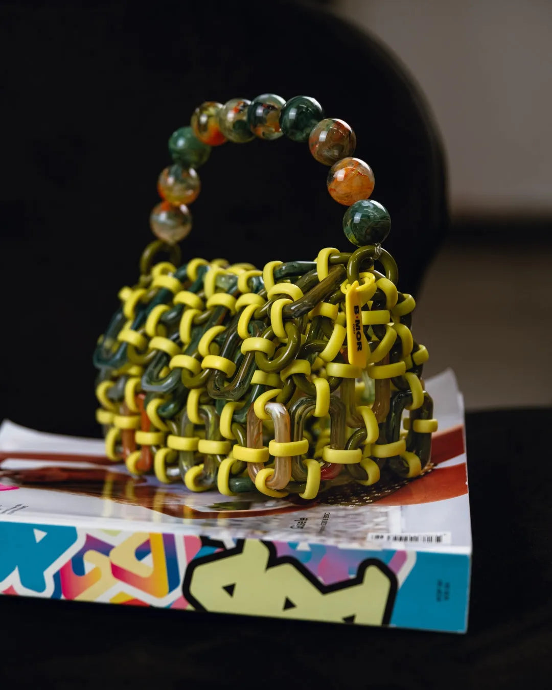 borsa a mano in resina multicolore lime, verde e arancione appoggiata