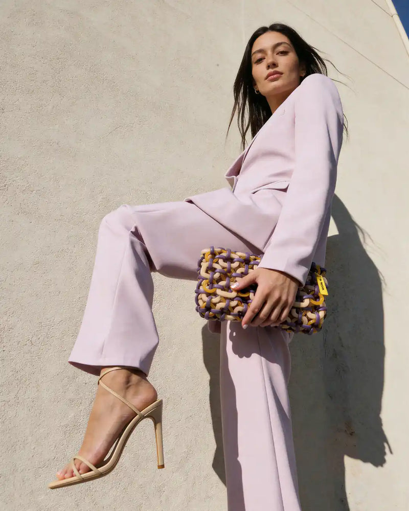 modella indossa borsa a mano in resina beige e viola