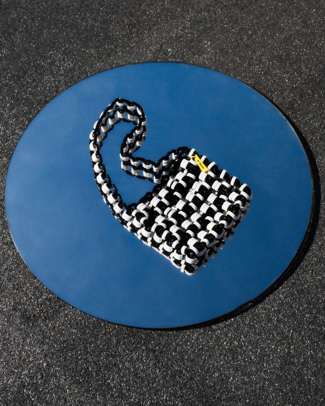 borsa a tracolla in resina bianco e nero appoggiata