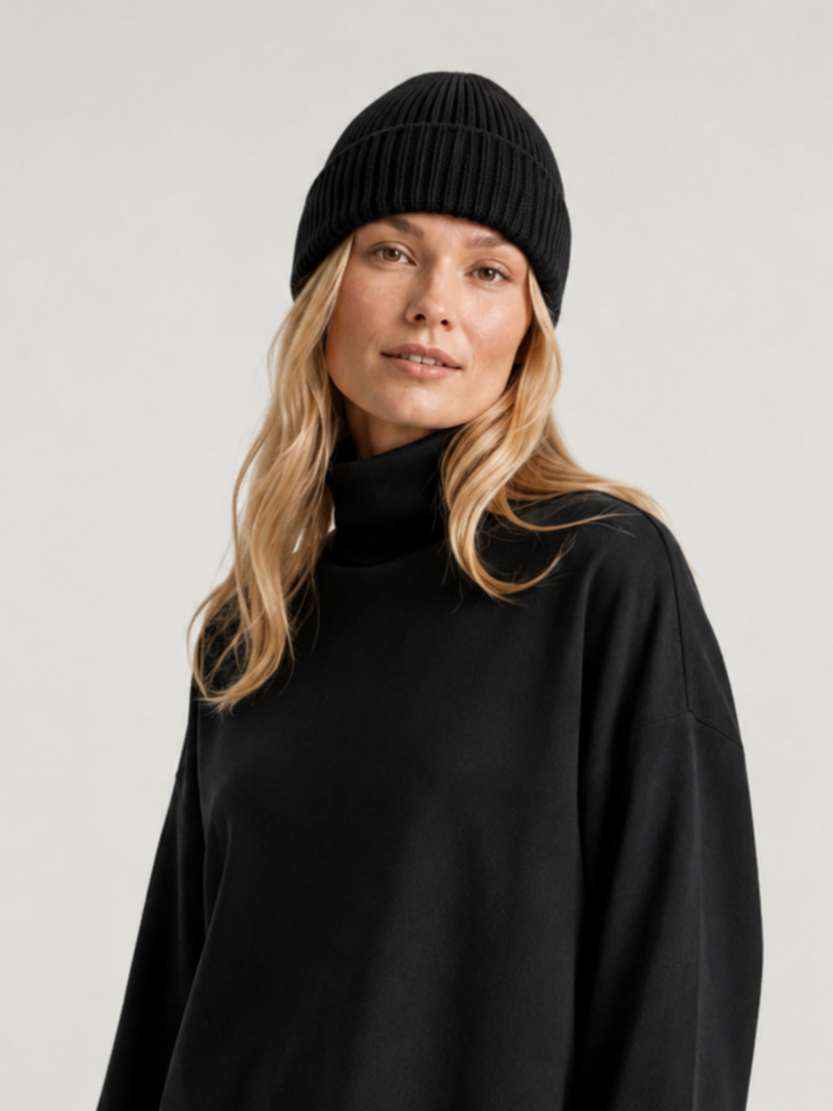 Modella indossa berretto beanie nero a coste verticali, risvolto alto e calotta arrotondata CHIA | BiMOR