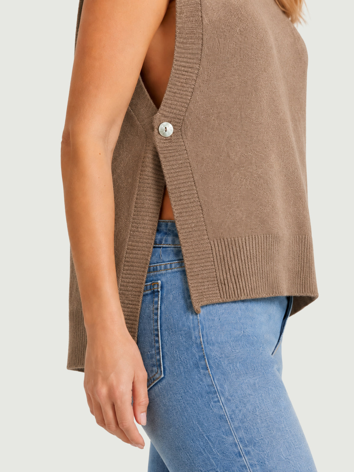 Dettaglio gilet smanicato color panna con aperture laterali chiuse da bottoni in madreperla