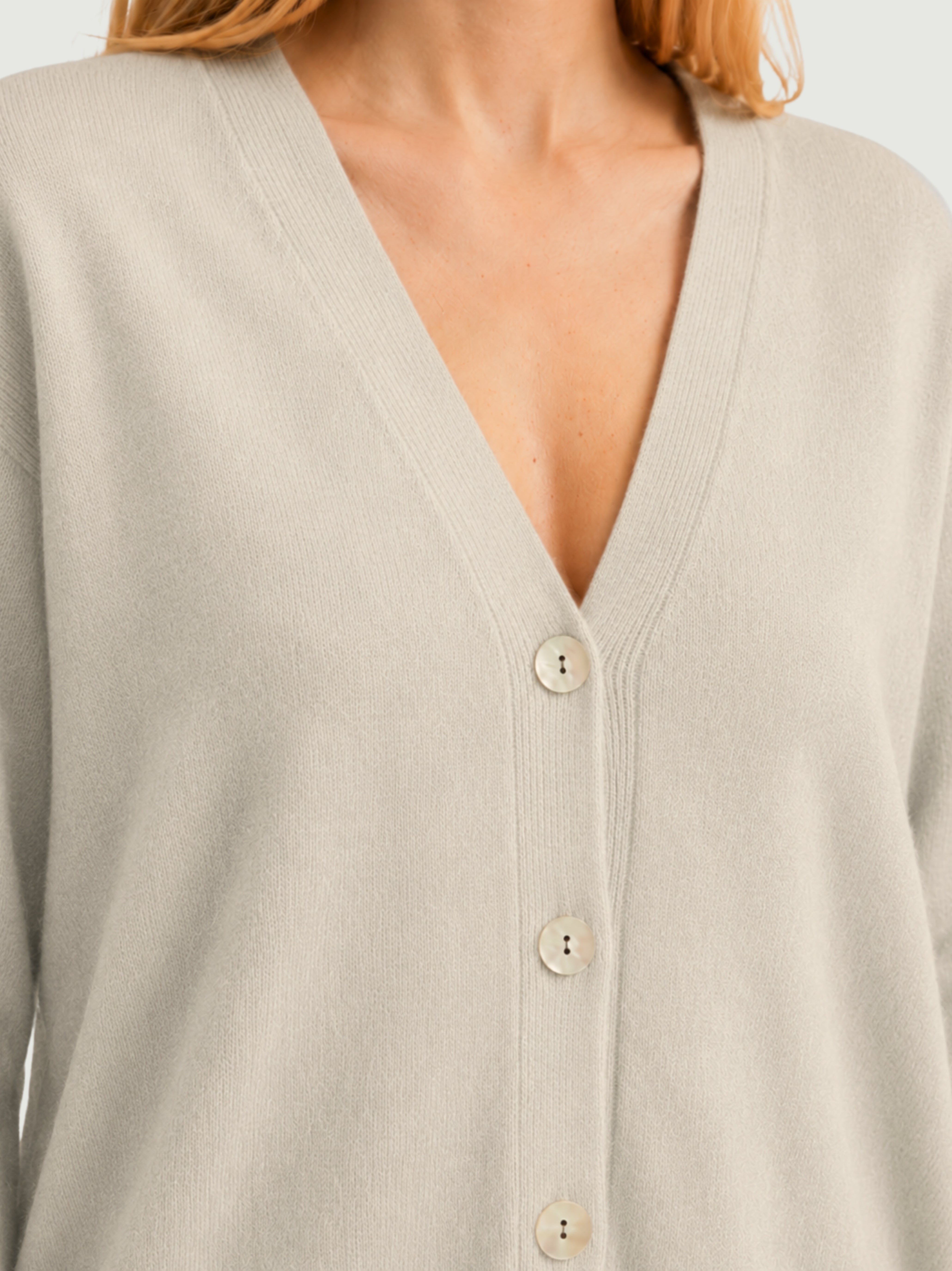 Dettaglio cardigan over bianco panna, scollo a V, manica lunga con polsino a costine, chiusura con bottoni effetto madreperla