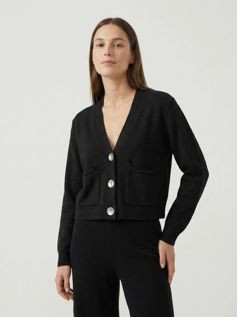 Modella indossa cardigan cropped nero con scollo a V, chiusura frontale con bottoni effetto madreperla, taschini applicati SOF - BiMOR
