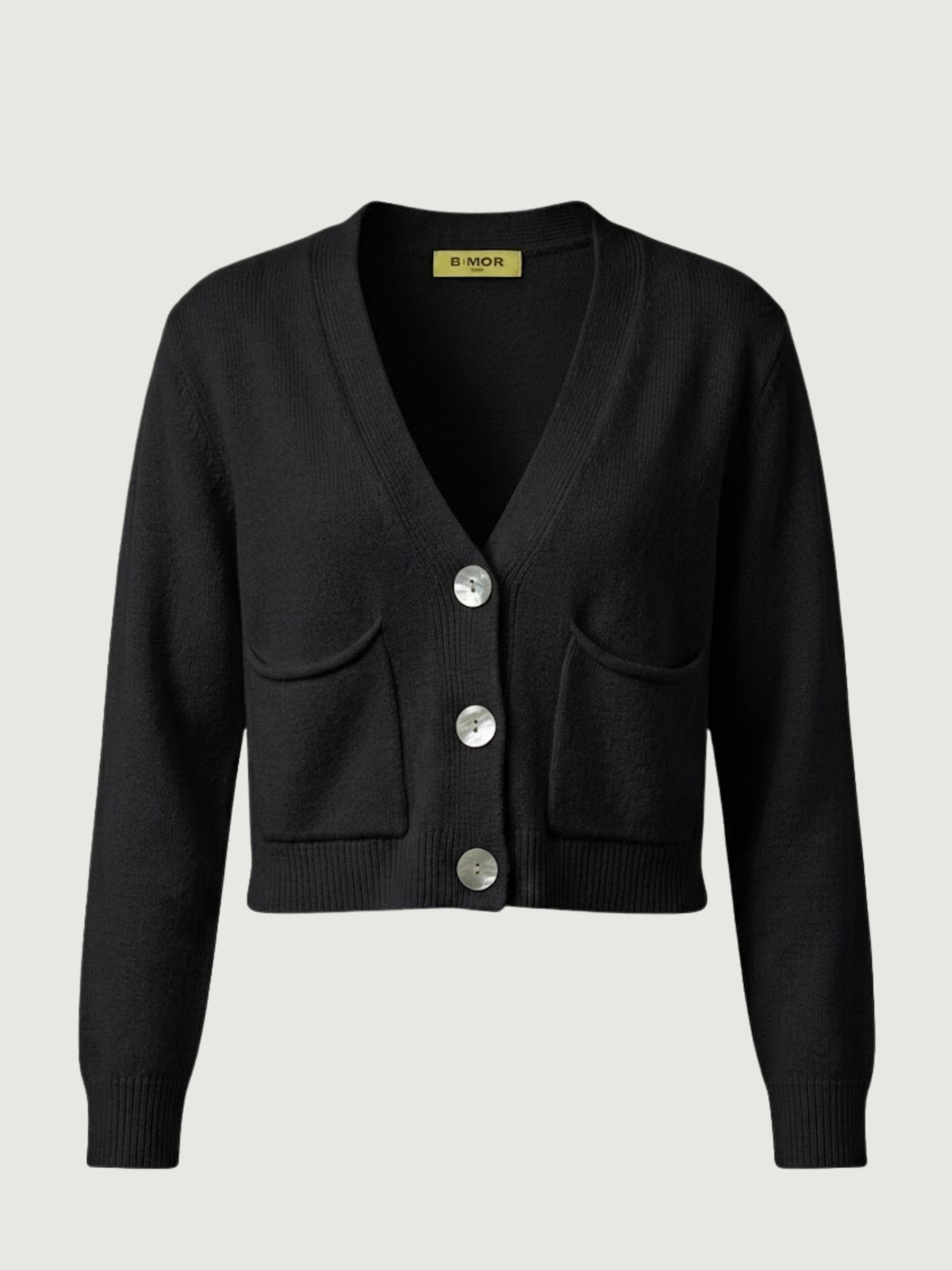 Vista frontale cardigan cropped nero con scollo a V, chiusura frontale con bottoni effetto madreperla, taschini applicati