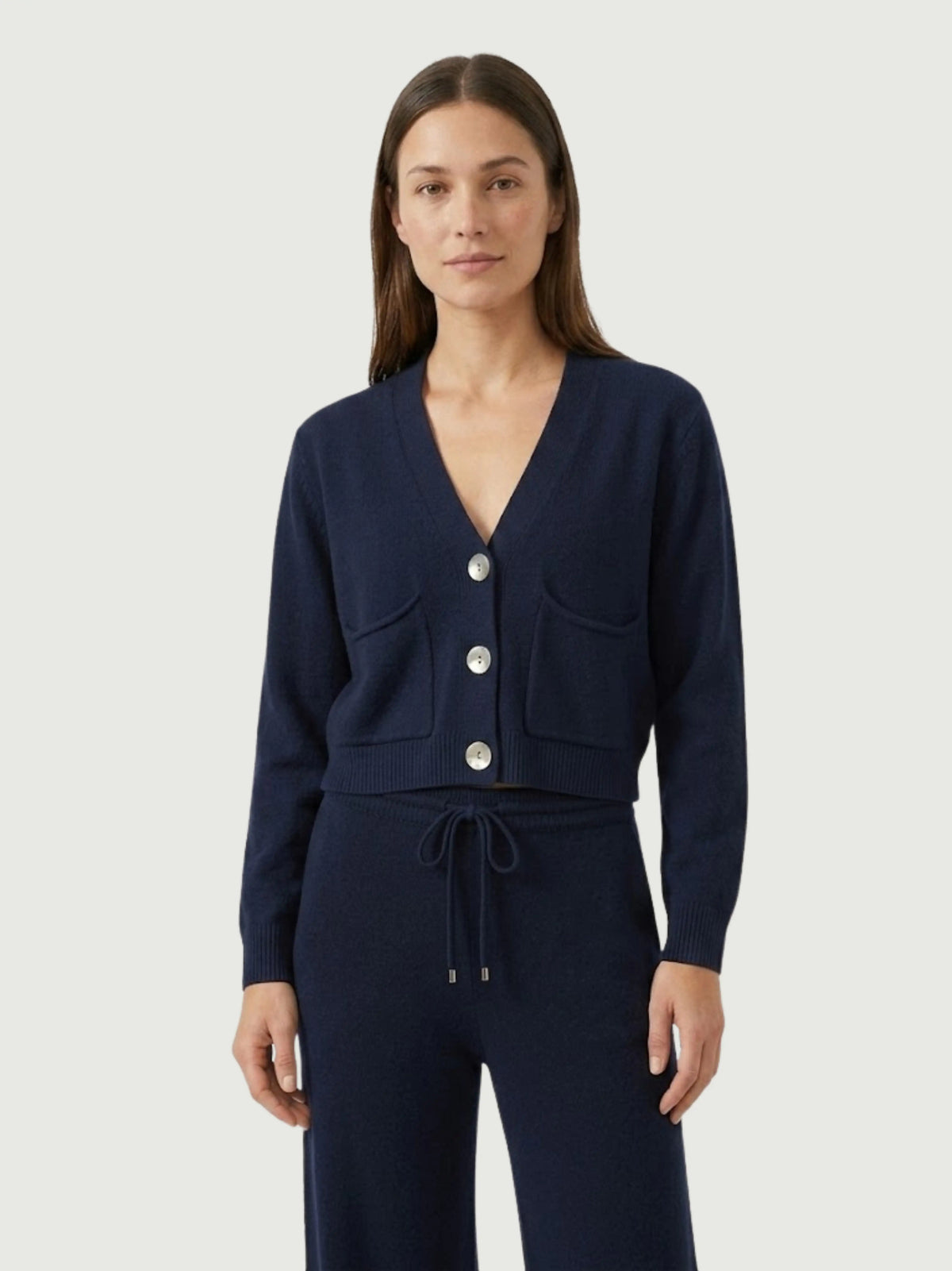 Modella indossa cardigan cropped blu scuro con scollo a V, chiusura frontale con bottoni effetto madreperla, taschini applicati SOF - BiMOR