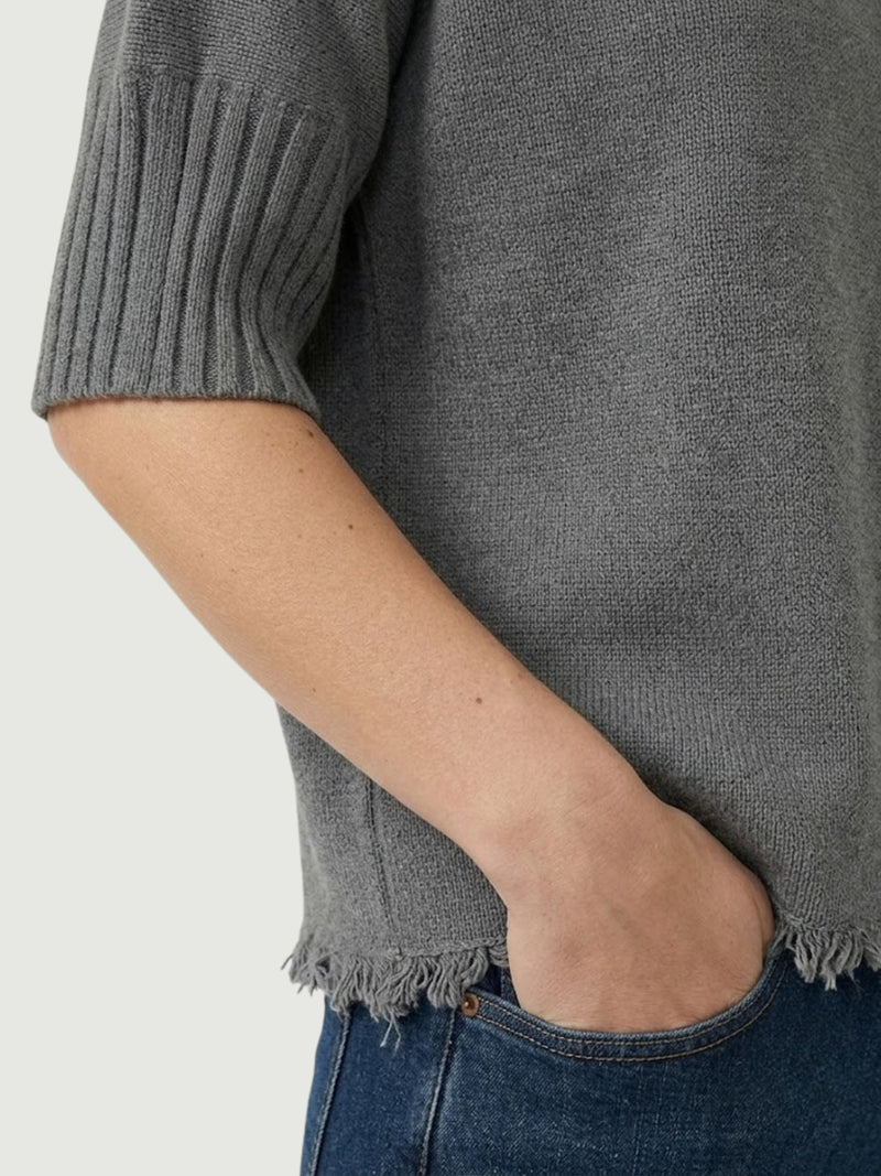 Dettaglio maglia lupetto grigia con manica a tre quarti e fondo sfrangiato