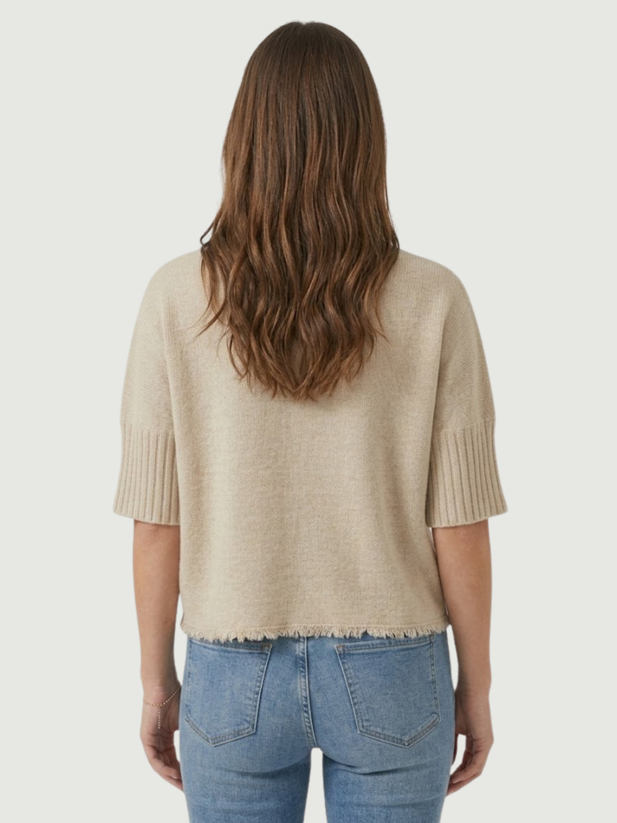 Vista posteriore modella indossa maglia lupetto beige con manica a tre quarti e fondo sfrangiato
