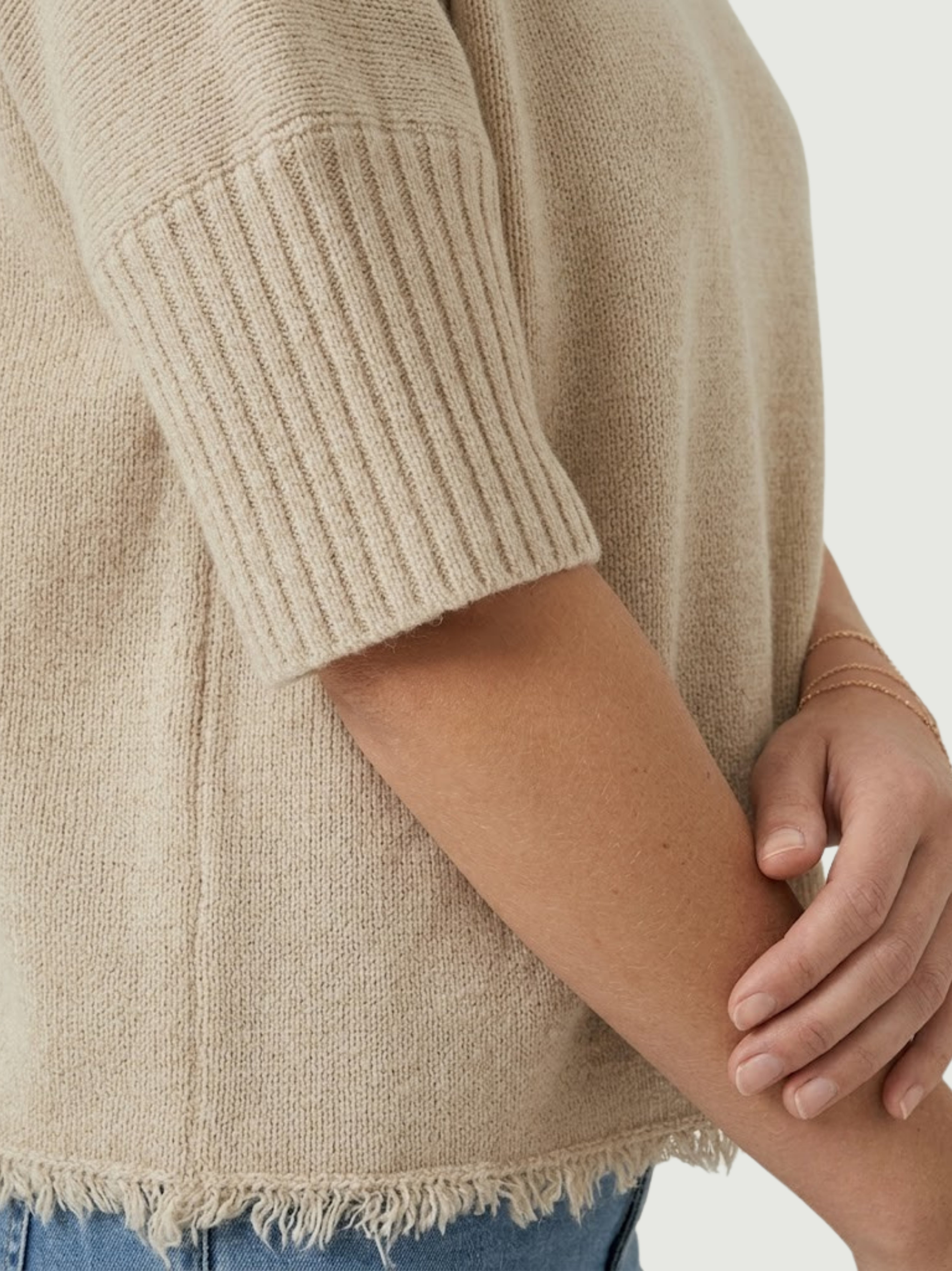 Dettaglio maglia lupetto beige con manica a tre quarti e fondo sfrangiato
