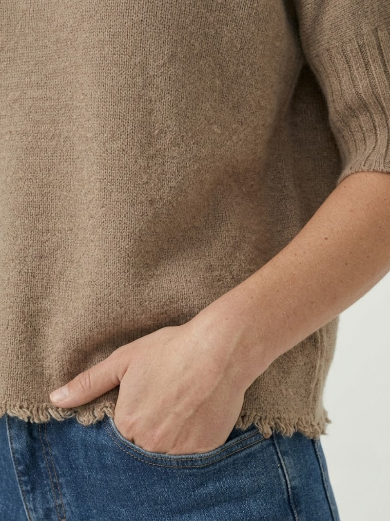 Dettaglio maglia lupetto nocciola con manica a tre quarti e fondo sfrangiato