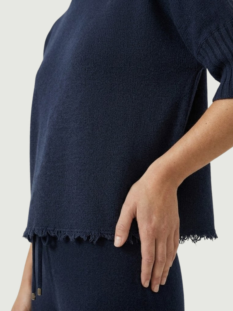 Dettaglio maglia lupetto blu scuro con manica a tre quarti e fondo sfrangiato