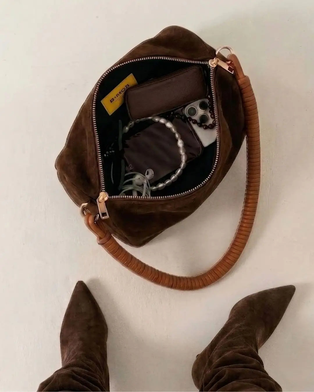 borsa a spalla bauletto in camoscio marrone con manico in pelle marrone appoggiata