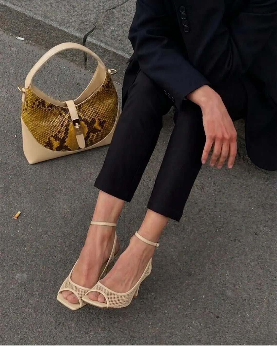 modella indossa borsa a spalla elegante in pelle di pitone giallo con manico e dettagli in pelle beige