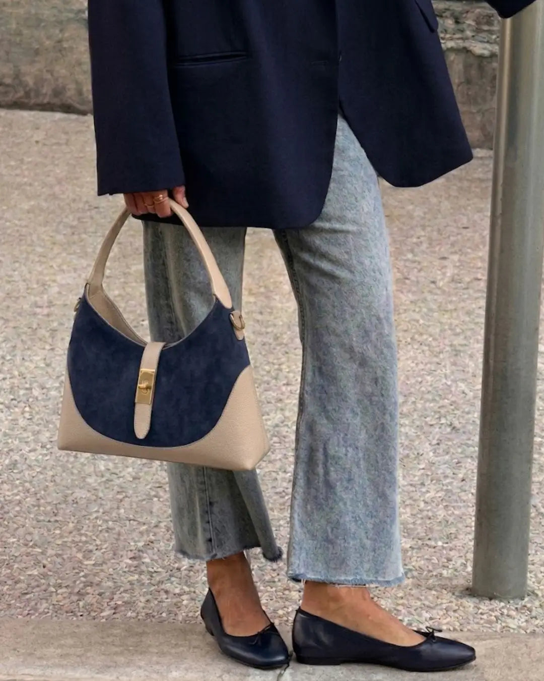 modella indossa borsa a spalla elegante in pelle di camoscio blu navy con manico e dettagli in pelle beige