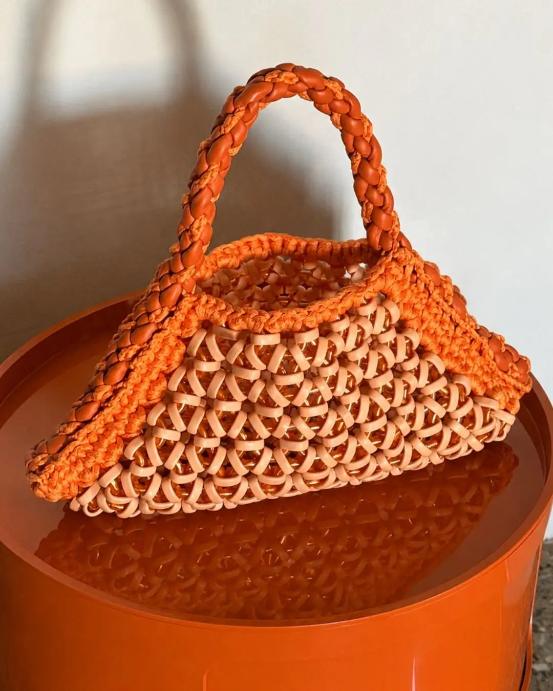borsa a mano in resina, pelle e cotone arancione appoggiata