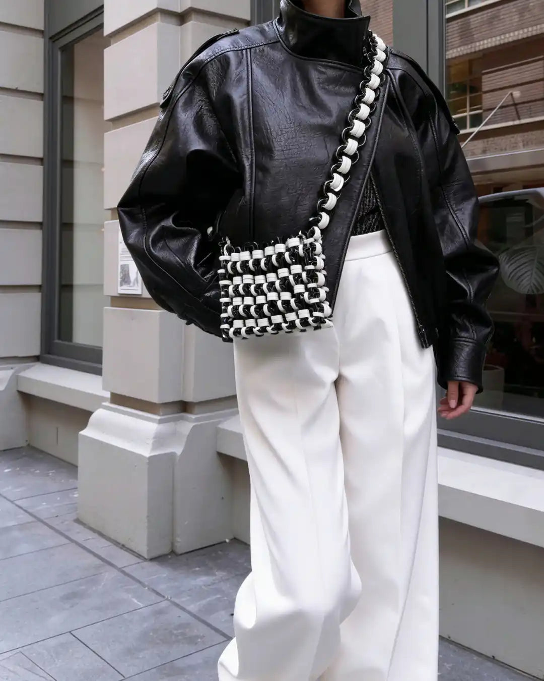 modella indossa borsa a tracolla in resina bianco e nero