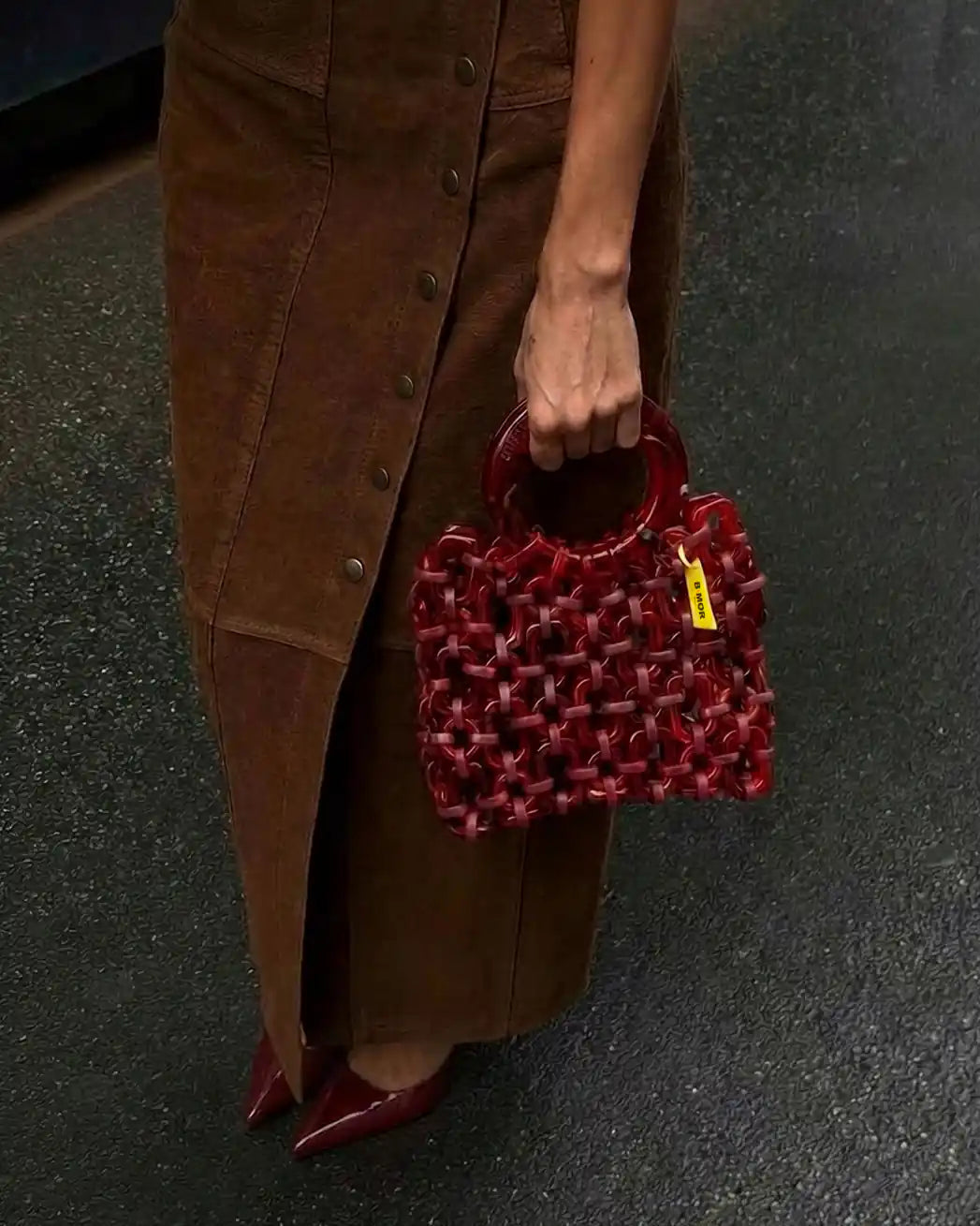 modella indossa borsa a mano in resina rosso ciliegia 